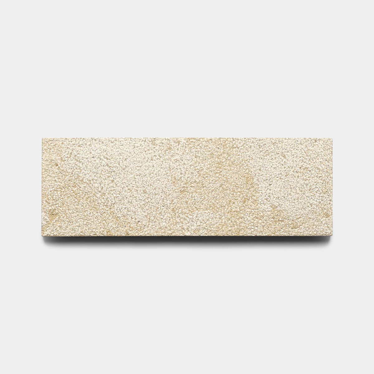 A Buff 4x12 + Bush Hammered beige rectangular handmade tile sample by Zia Tile is displayed against a plain white background with a soft shadow underneath.