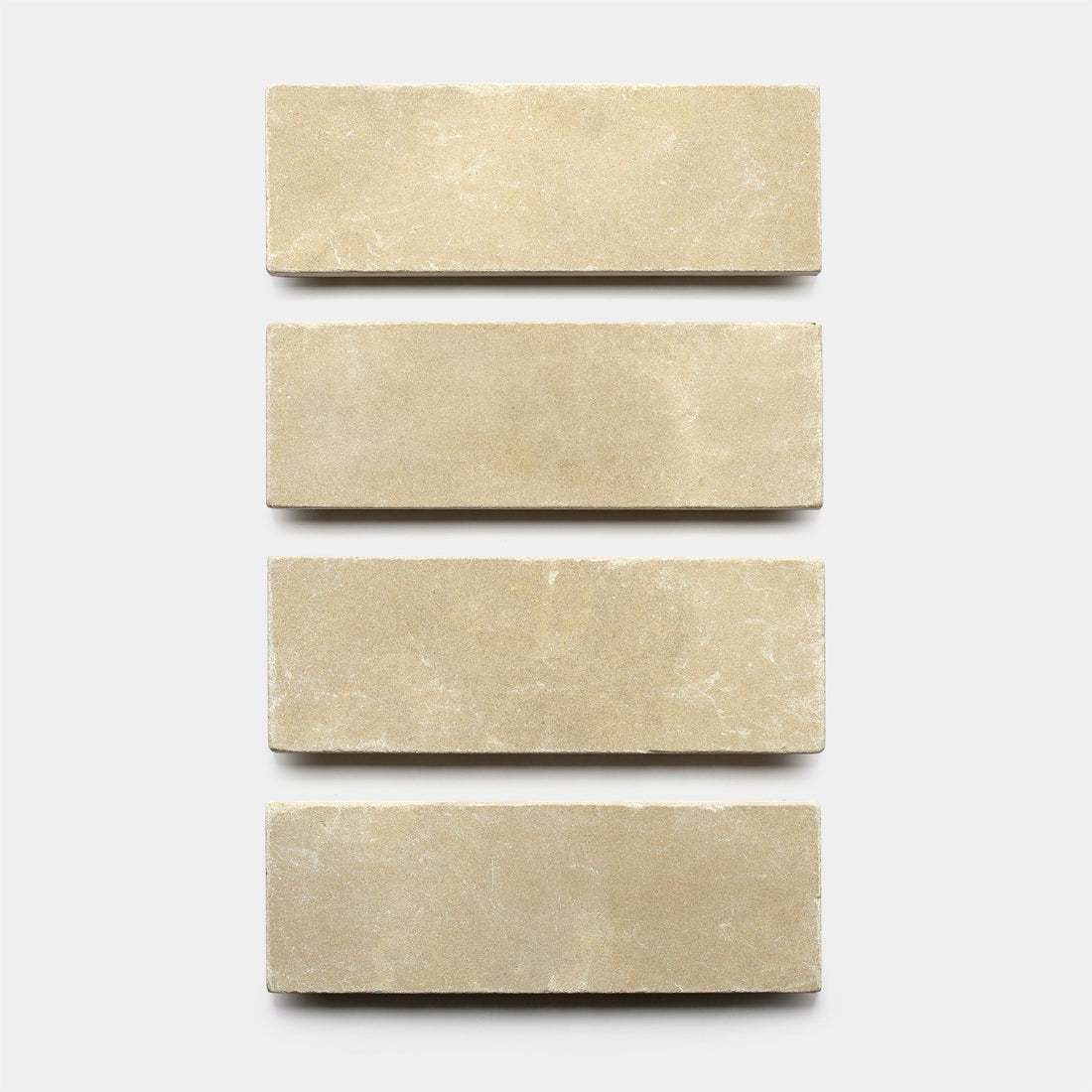 Four Buff 4x12 + Honed tiles by Zia Tile are arranged vertically in a single column against a plain white background, showcasing their slightly textured, natural stone look.