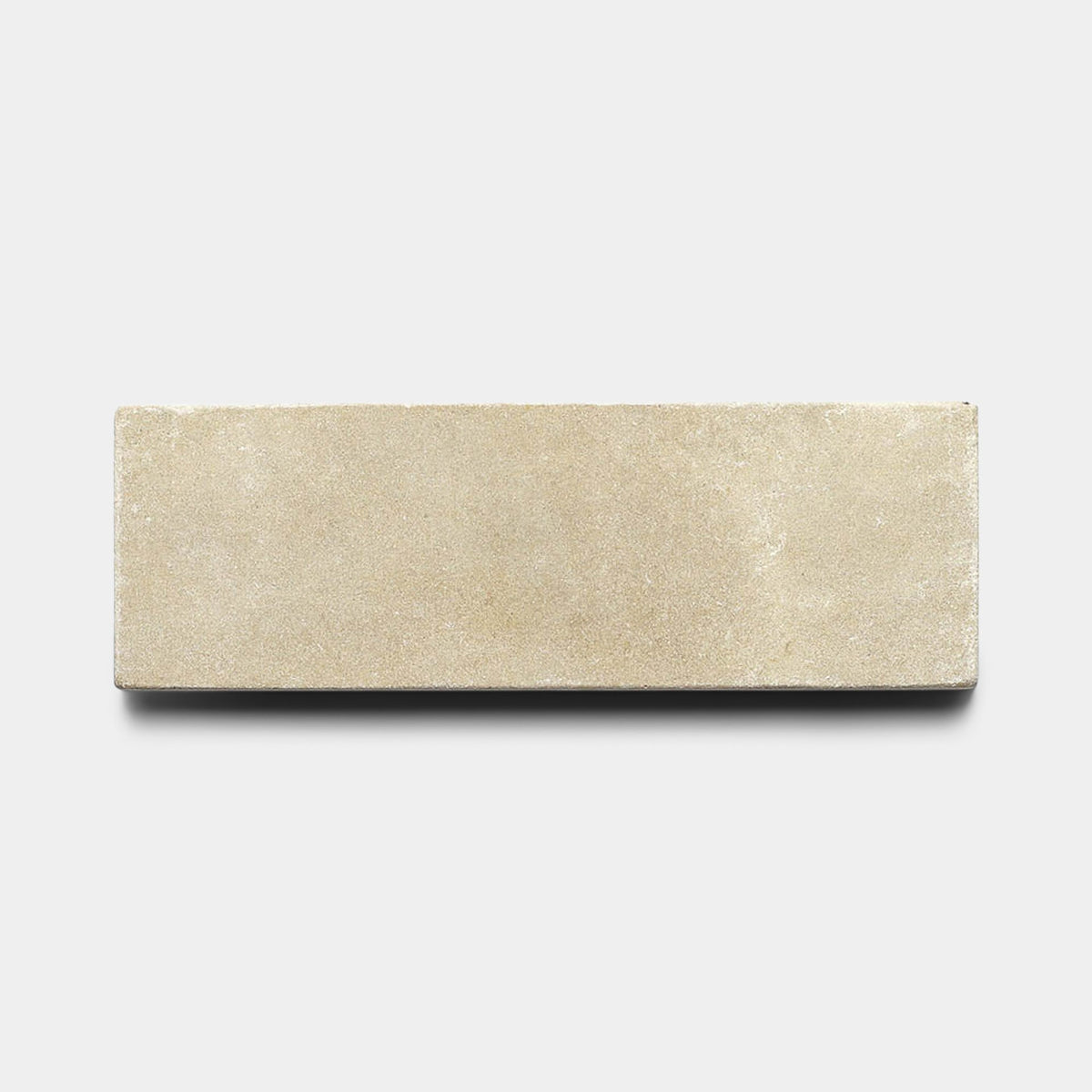 A Buff 4x12 + Honed cement tile sample by Zia Tile, featuring a rectangular, beige design with a smooth finish, is centered on a plain white background.