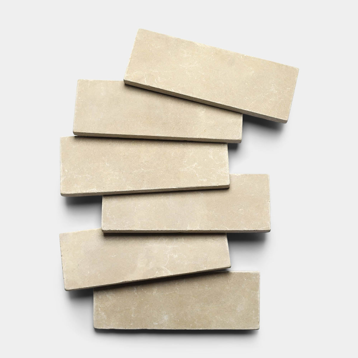 Five Buff 4x12 + Honed, Sample tiles from Zia Tile are stacked in a slightly staggered arrangement on a white background, with each handmade tile overlapping the one below.