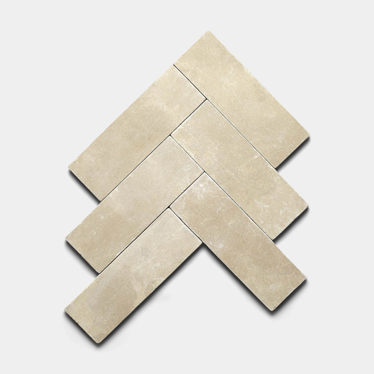 Five Buff 4x12 Honed cement tiles by Zia Tile are arranged in a herringbone pattern on a white background. The handmade beige tiles feature a subtle texture and cast soft shadows.