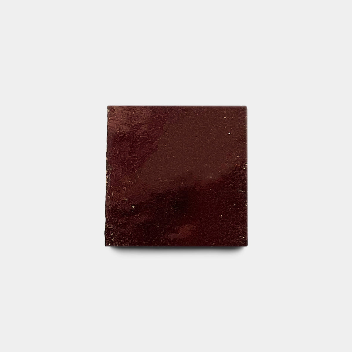 A single Burnt Sugar 2x2 sample tile from Zia Tile, with a smooth, glossy finish, is displayed on a plain light gray background.