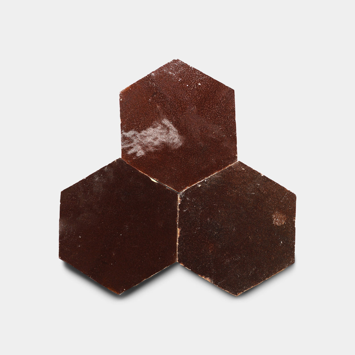 Three Burnt Sugar 2x6 sample tiles from Zia Tile, handcrafted in dark brown with a slightly rough, textured surface, are arranged edge-to-edge in a cluster on a plain white background.