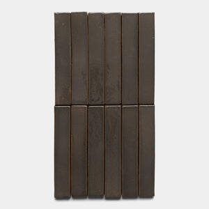 Twelve Zia Tile Cacao Mini Bar dark brown rectangular boxes are stacked in two vertical rows of six against a plain white background.