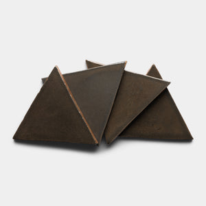 Four Cacao Triangle tiles by Zia Tile, made of dark ceramic, are arranged in a layered, overlapping triangular pattern on a white background.