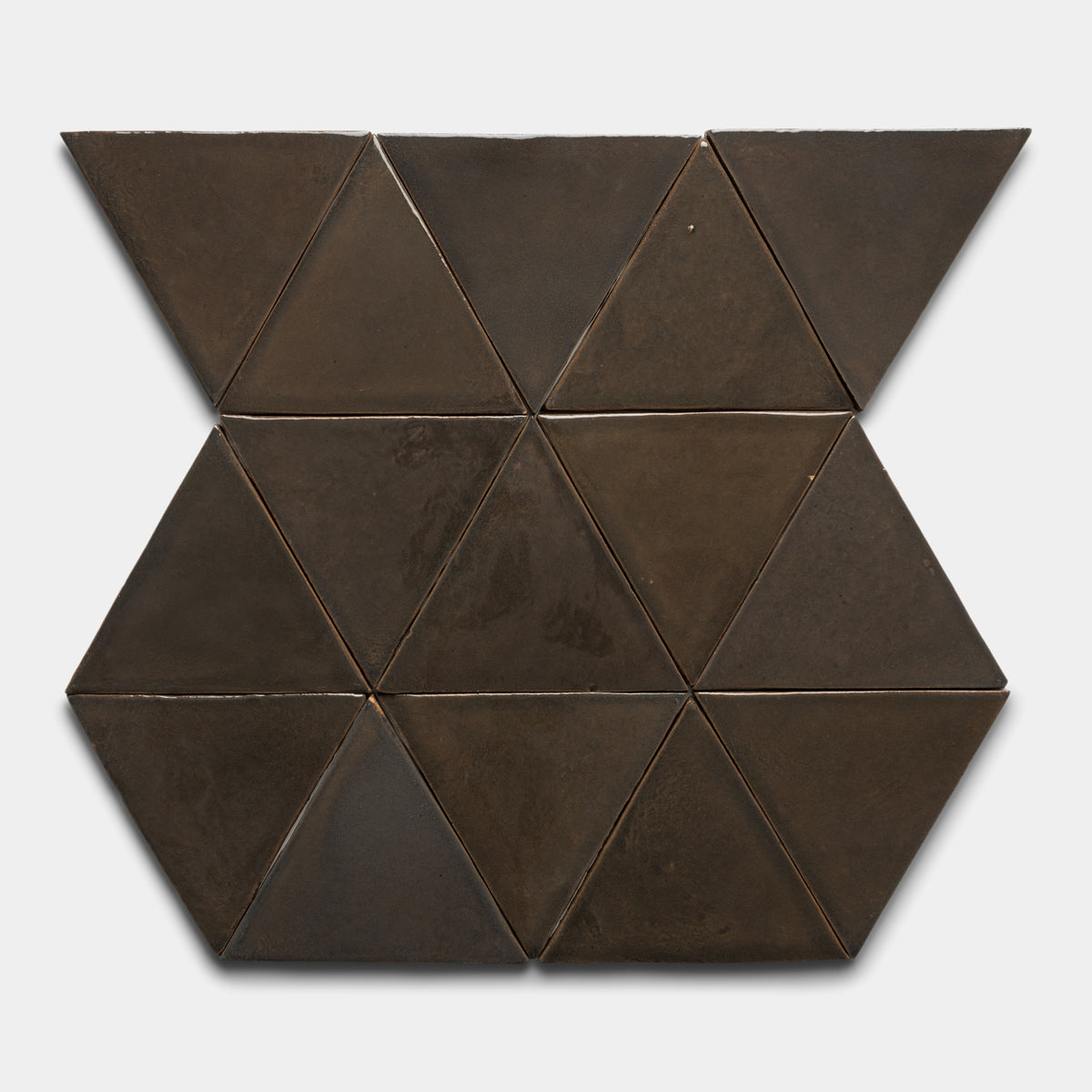 Twelve Cacao Triangle tiles by Zia Tile in dark brown ceramic are arranged symmetrically on a light background, creating a large hexagon with two triangles extending outward on opposite sides.