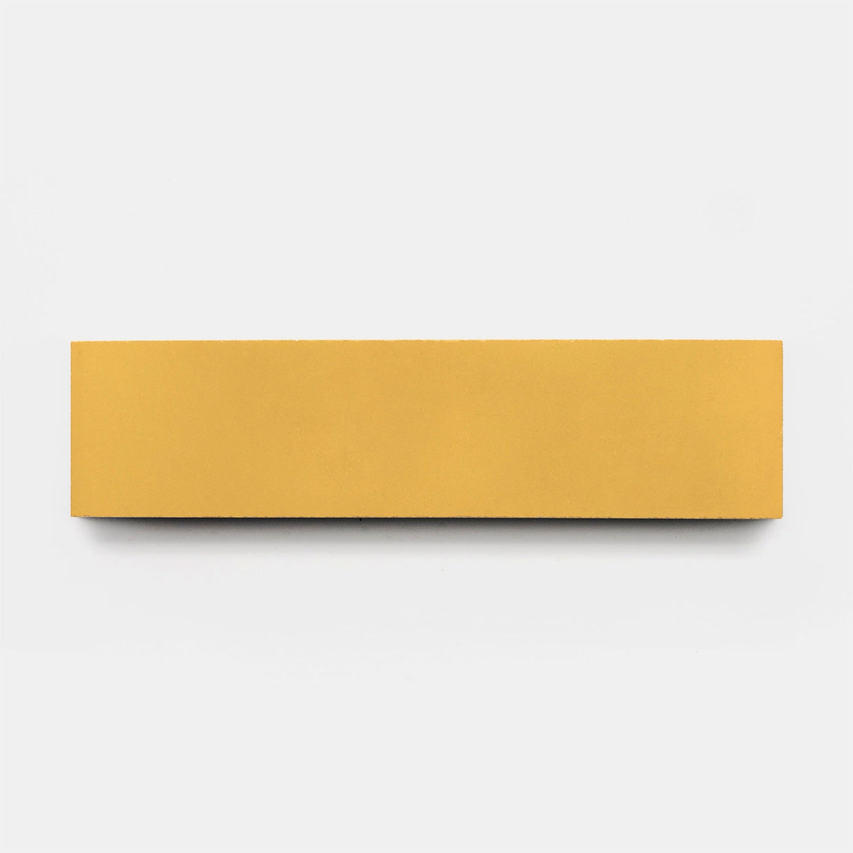 A rectangular Cadmium 2x6 sample tile by Zia Tile, in a vibrant yellow hue, is displayed horizontally on a plain white background, evoking the smooth finish of handcrafted ceramics.