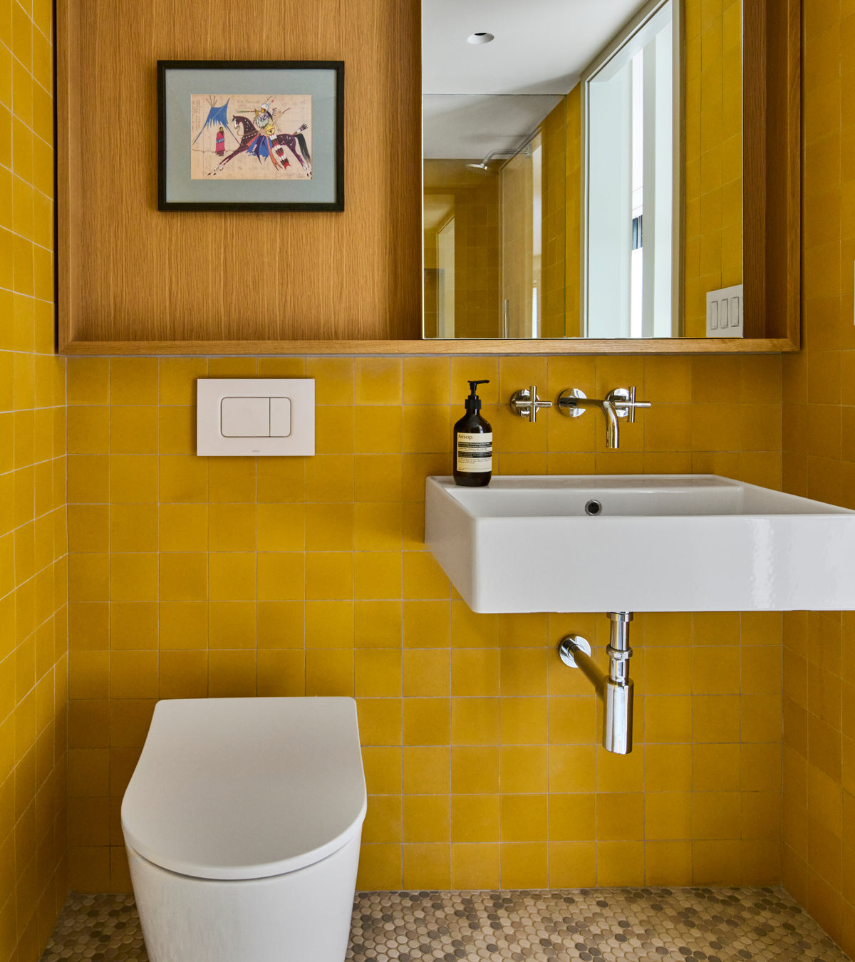 A bathroom with Cadmium 4x4 cement tile wall squares, a floating white sink, a wall-mounted toilet, and a wooden mirror frame above the vanity.
