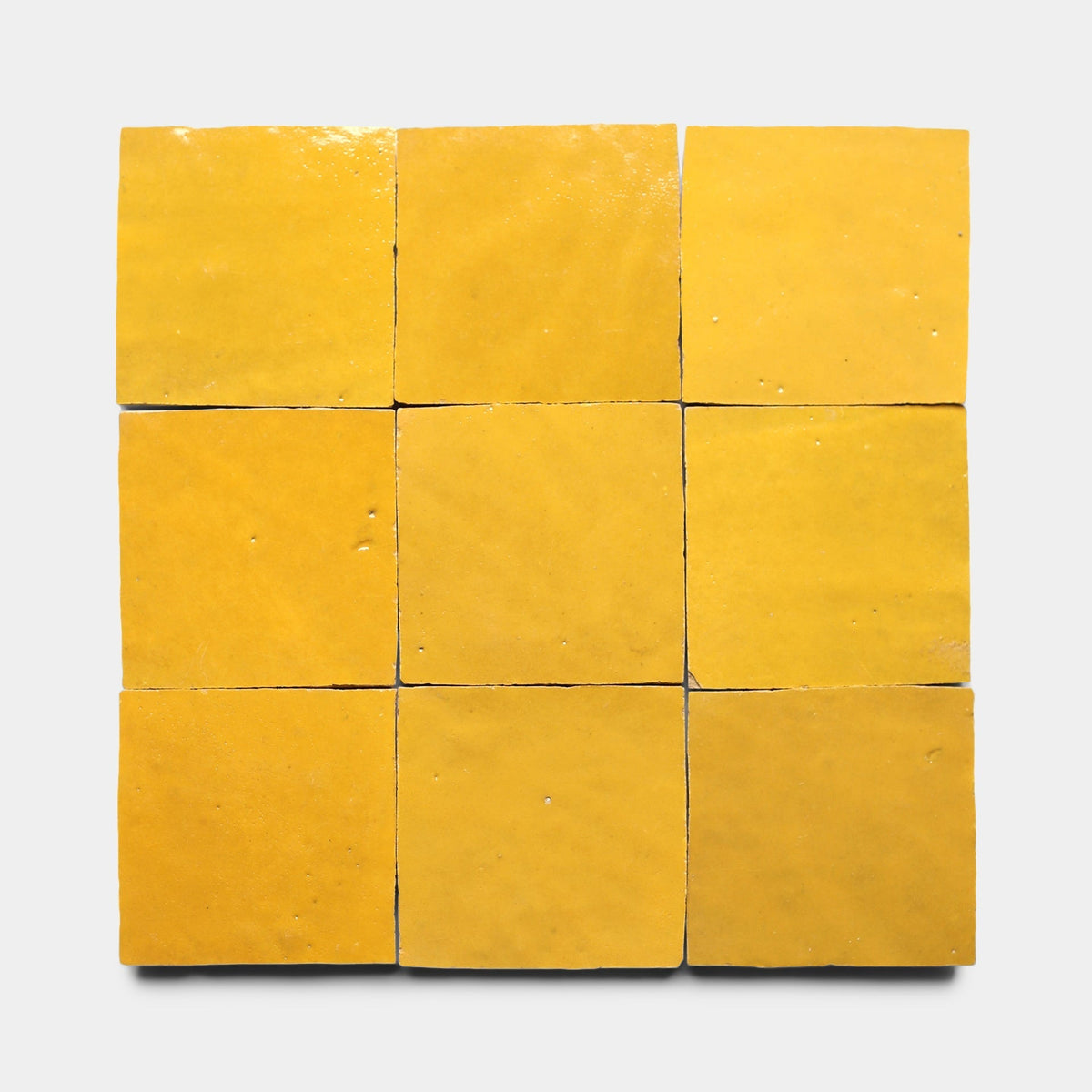Nine Cadmium 2x6 tiles by Zia Tile are arranged in a 3x3 grid on a plain white background. The handmade tiles have a glossy, slightly uneven surface and imperfect edges.