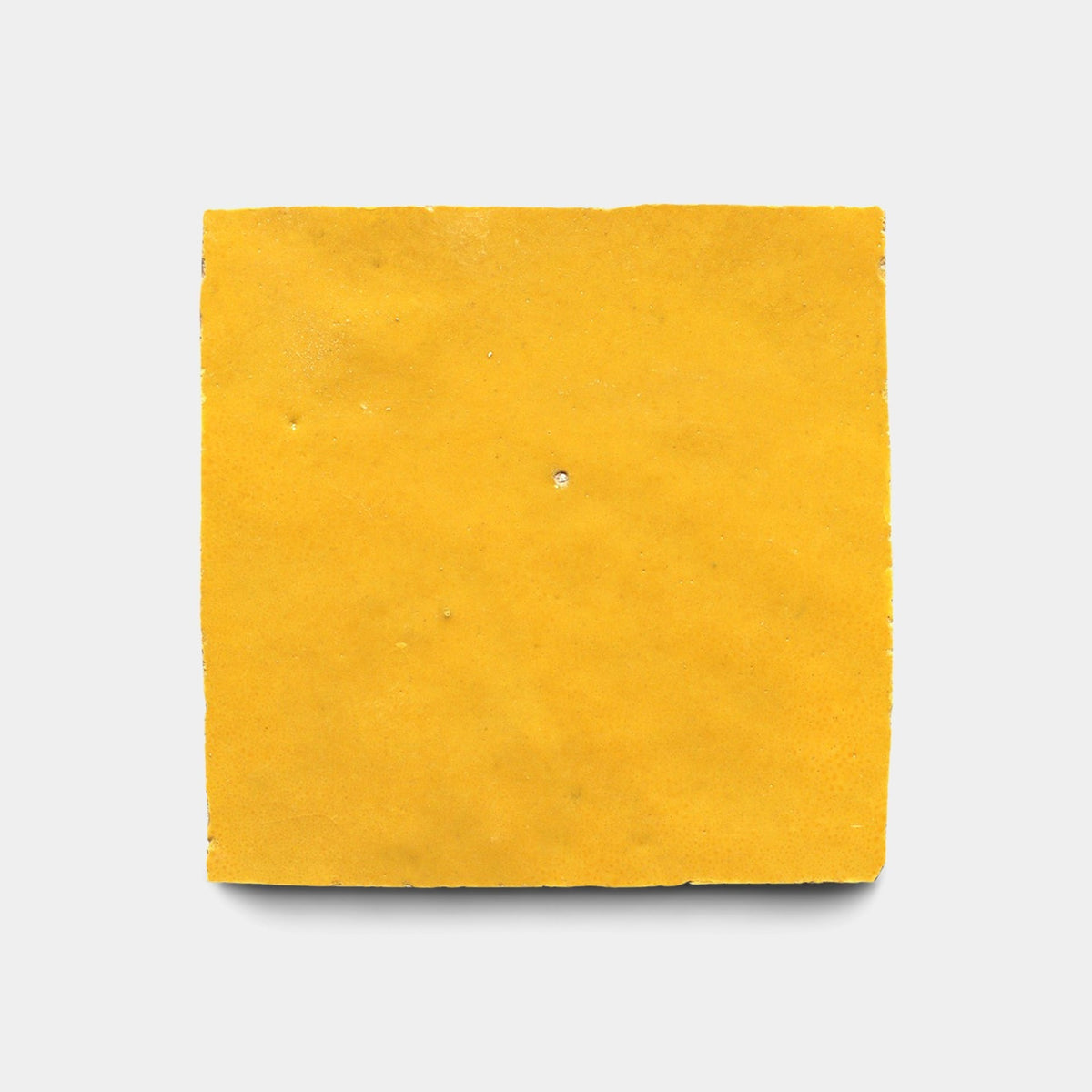 A single piece of Zia Tile's Cadmium 2x6, Sample is centered on a white background, its smooth yellow surface evoking the look of handmade tiles from the classic Zia Tile collection.