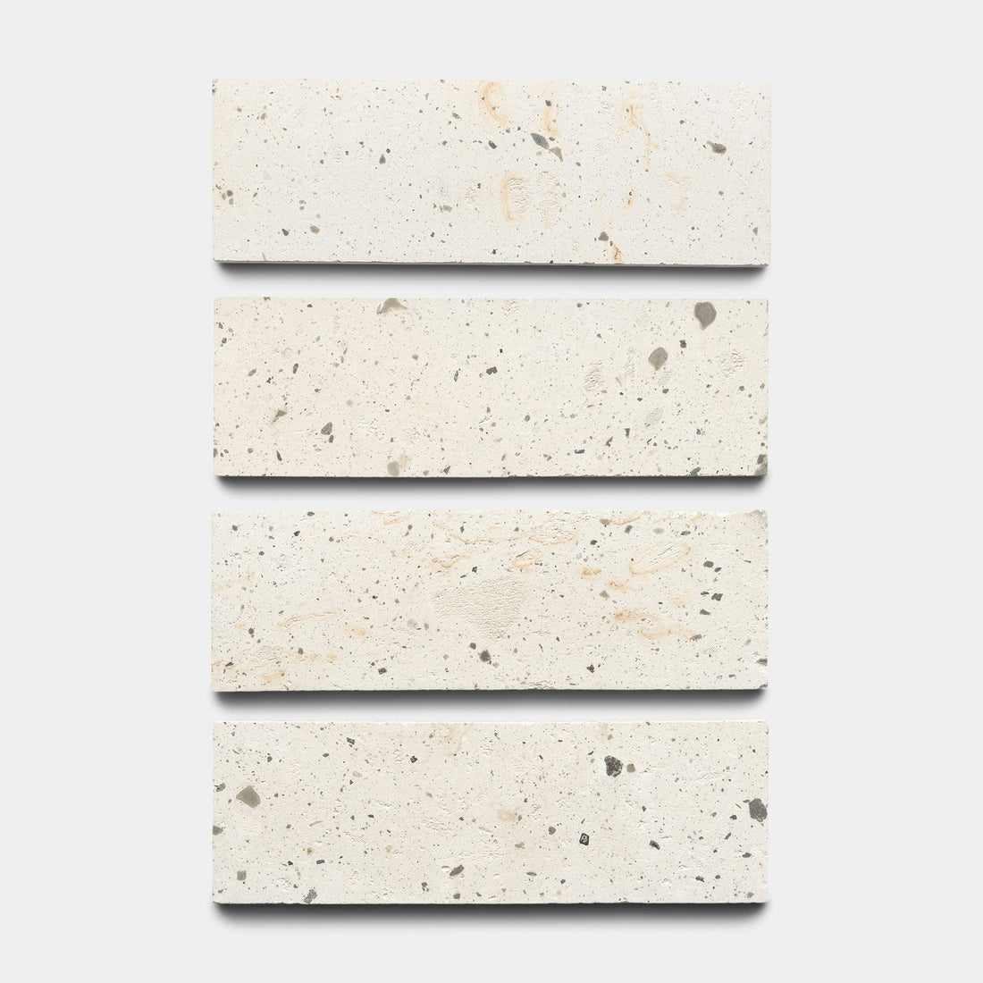 Four rectangular, cream-colored tiles with subtle gray and beige speckled patterns are arranged vertically in a row against a white background.