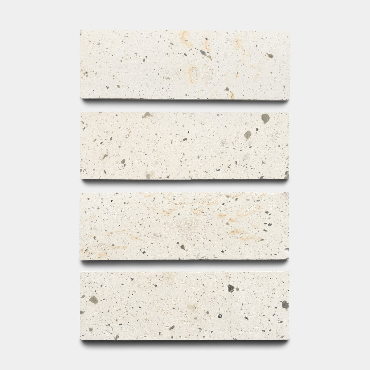 Four rectangular, cream-colored tiles with subtle gray and beige speckled patterns are arranged vertically in a row against a white background.