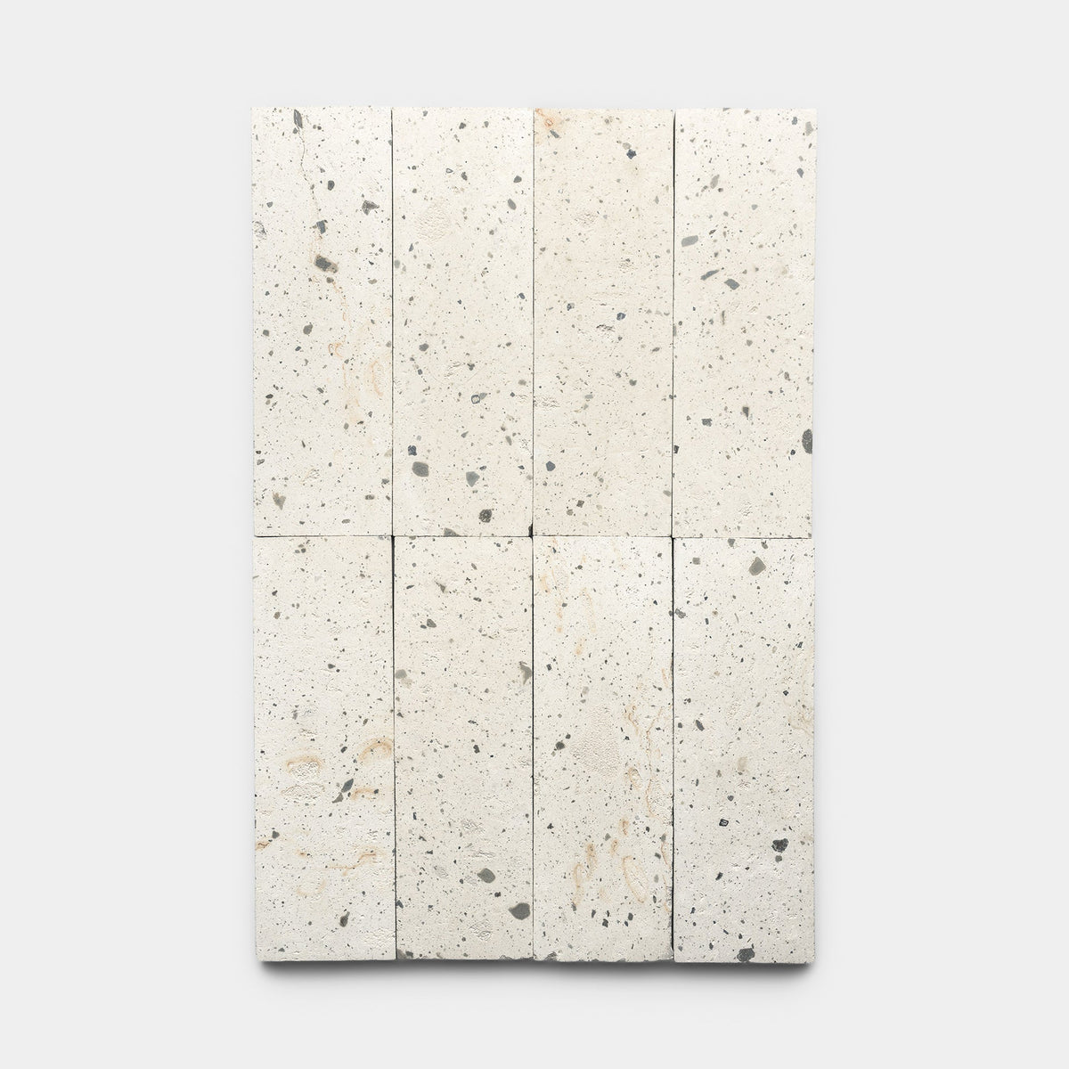 Eight rectangular, light-colored stone tiles with small, irregular gray and beige speckles are arranged in two columns and four rows on a plain, light gray background.