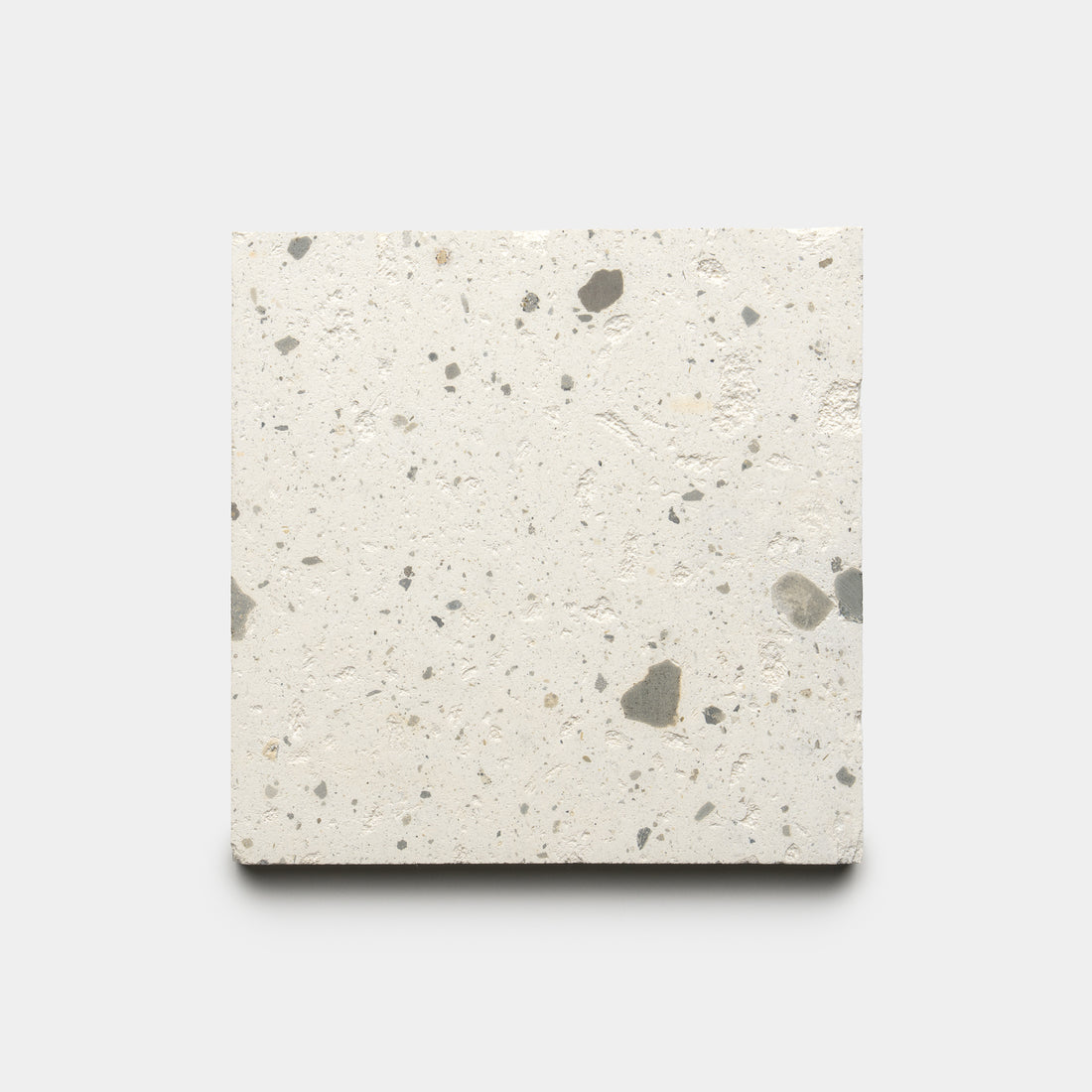 The Caldera 6x6 by Zia Tile is a square, light-toned concrete tile with scattered small dark and gray specks, displayed on a plain white background.