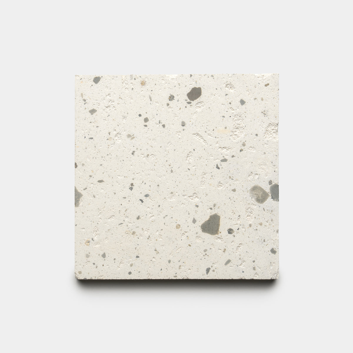 The Caldera 6x6 by Zia Tile is a square, light-toned concrete tile with scattered small dark and gray specks, displayed on a plain white background.