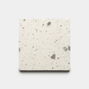 The Caldera 6x6 by Zia Tile is a square, light-toned concrete tile with scattered small dark and gray specks, displayed on a plain white background.