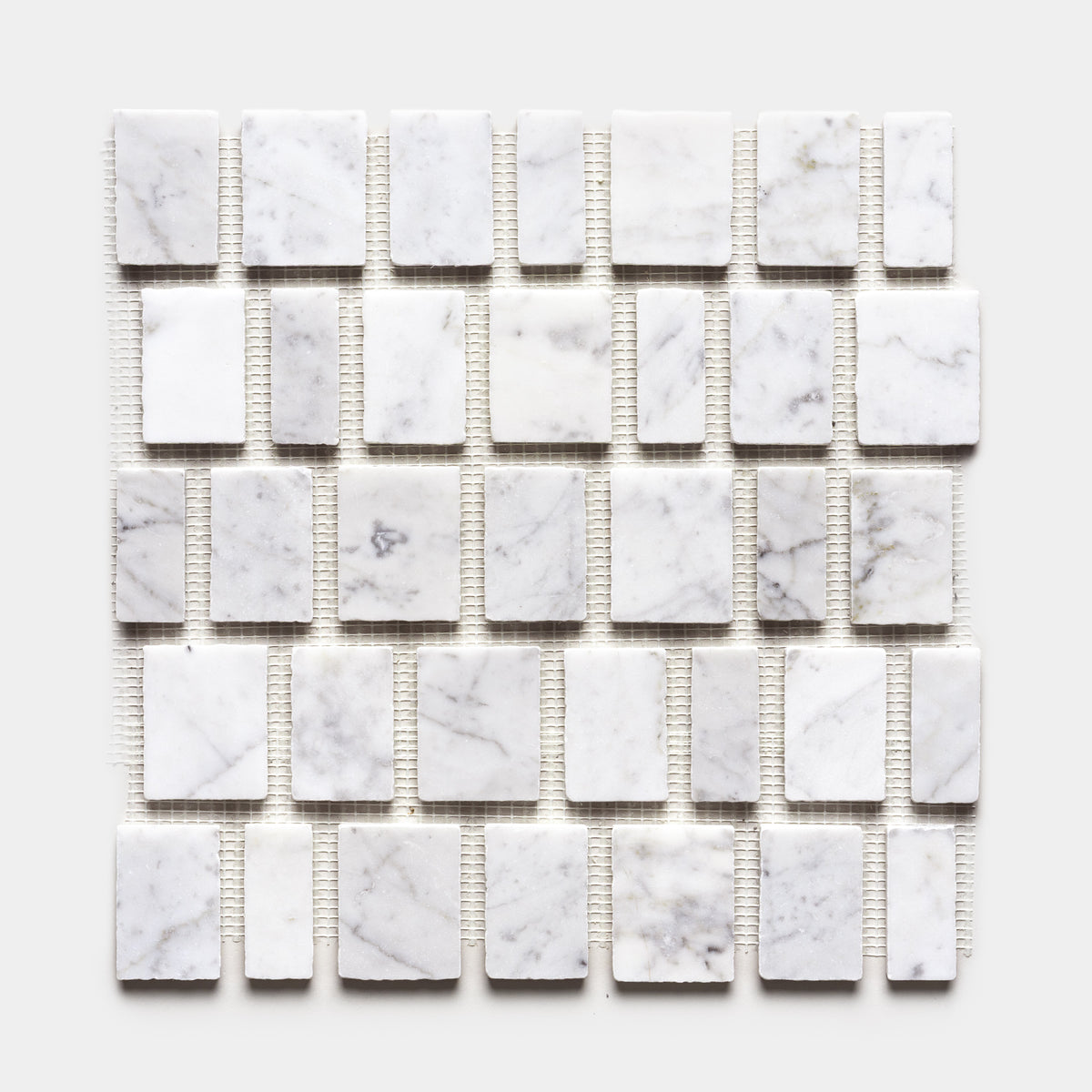 A grid of Scarpa in Carrara sample tiles by Zia Tile, featuring rectangular white marble with subtle gray veining, is evenly arranged on mesh backing and shown against a plain white background.