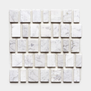 A grid of Scarpa in Carrara sample tiles by Zia Tile, featuring rectangular white marble with subtle gray veining, is evenly arranged on mesh backing and shown against a plain white background.