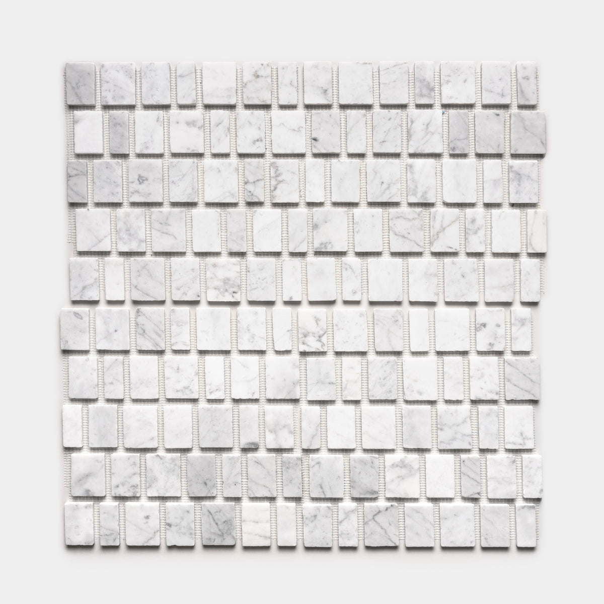 Scarpa in Carrara by Zia Tile features a grid of small, rectangular white marble tiles with subtle gray veining, arranged in even rows on mesh backing and displayed against a plain white background.