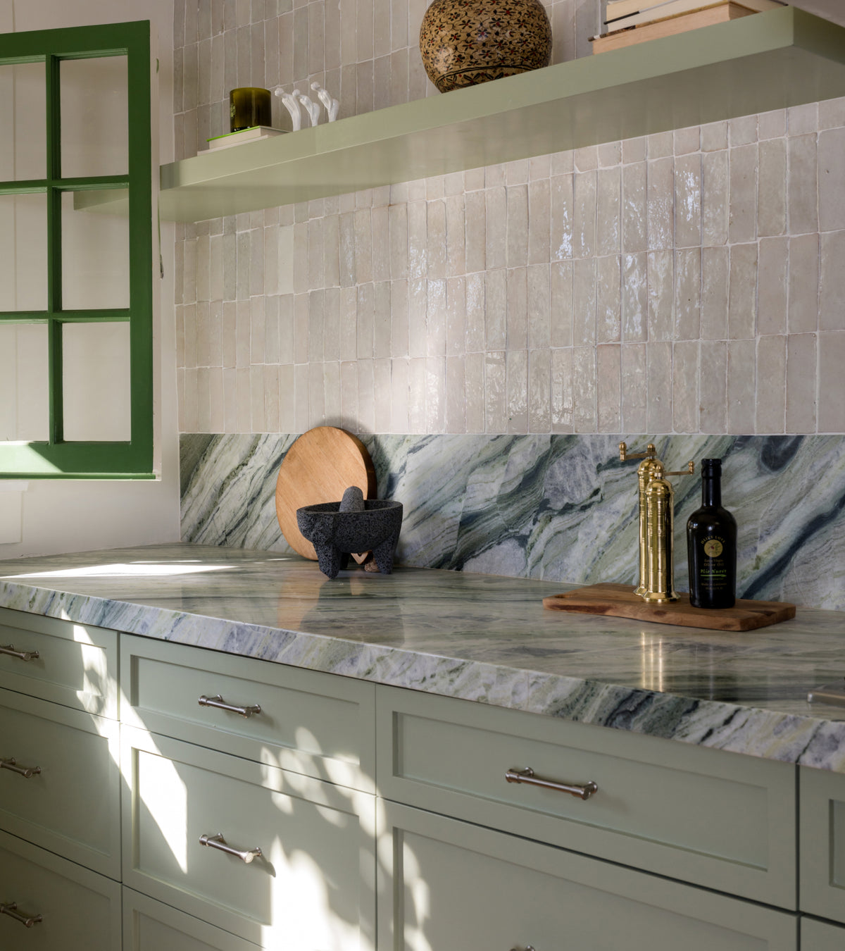 Off-white, handmade Casablanca 2x6 Moroccan zellige wall tiles by Zia Tile installed in a vertical brick pattern above a green-veined marble countertop and backsplash.