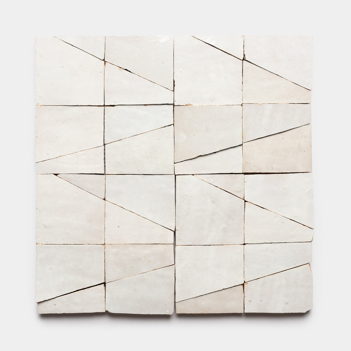 Sixteen Atlas 5 square white tiles by Zia Tile are arranged in a grid, each featuring an angled line that forms striking geometric patterns across a plain, light-colored background.