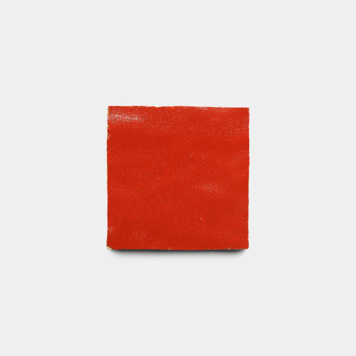 A single Cayenne 2x2 tile sample by Zia Tile, in bright red and square-shaped like handmade art, is centered on a plain white background.