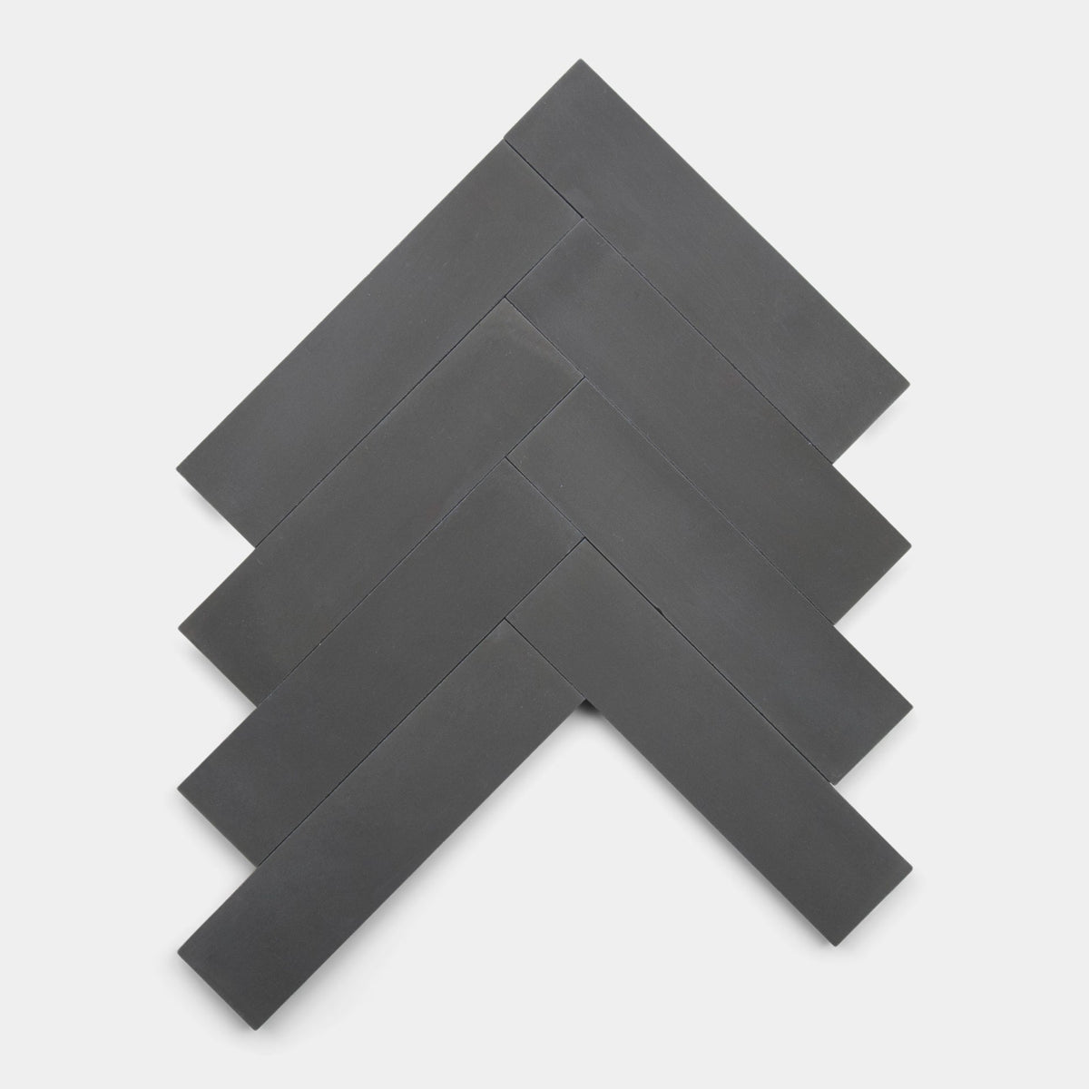 Six rectangular, matte Charcoal 2x8 cement tiles by vendor-unknown are arranged in a herringbone pattern on a white background. The handmade tiles overlap at angles, creating a zigzag, arrow-like design.