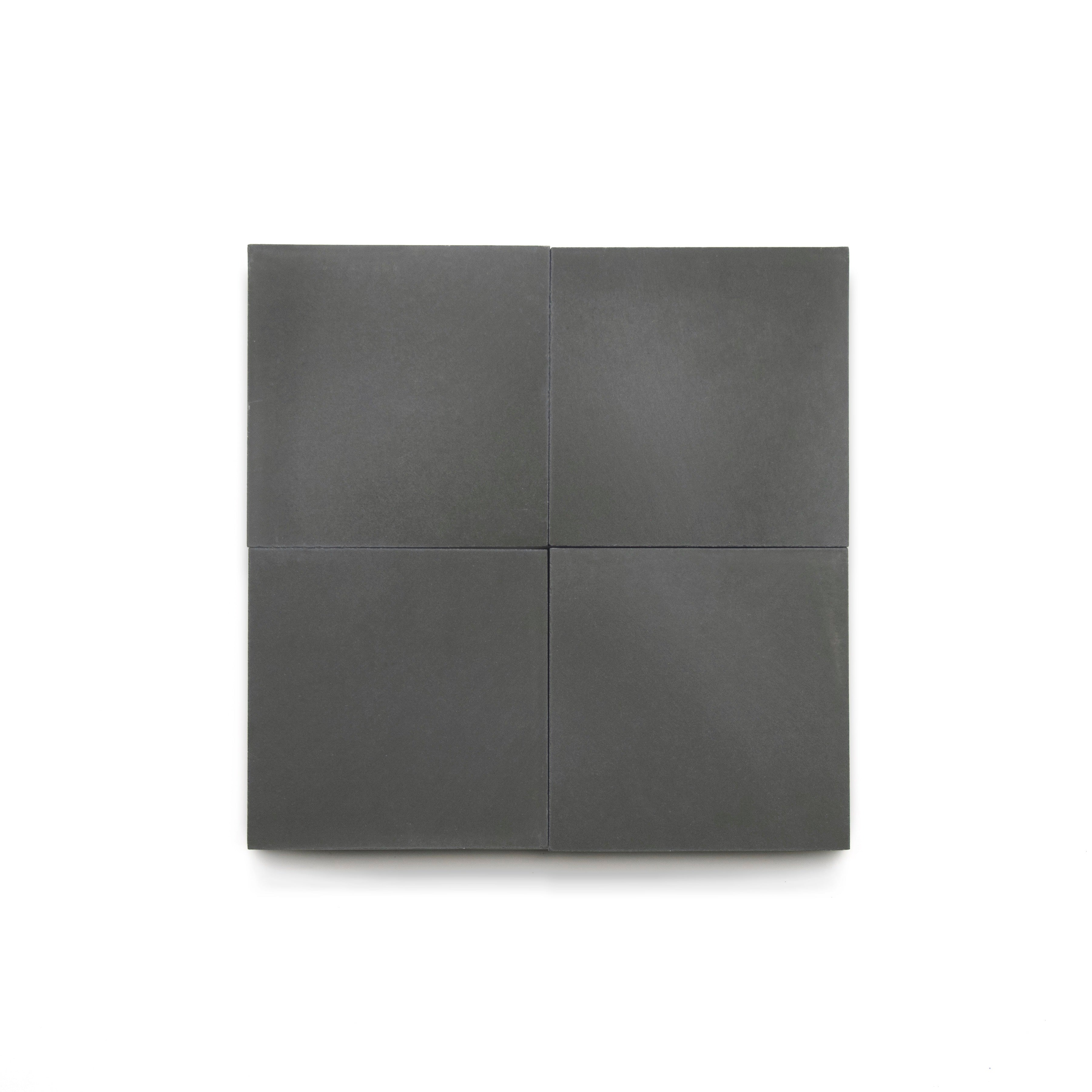 Four matte, dark gray Charcoal 4x4 tiles are arranged in a neat 2x2 grid on a plain white background, highlighting their modern look—ideal for bathroom floors or a stylish kitchen backsplash.