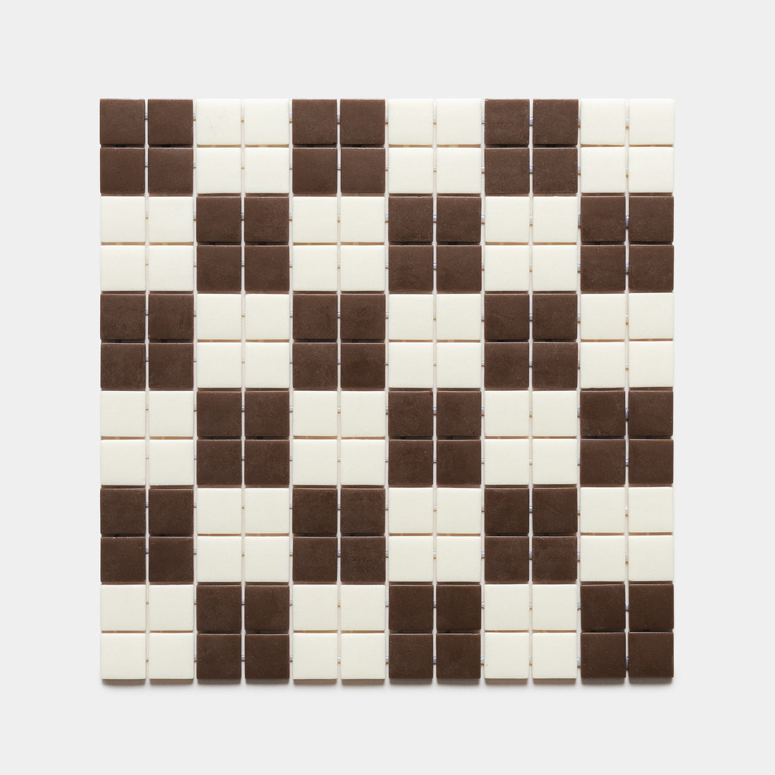 The Cheque Marmot + Milk tiles by Zia Tile feature a grid of small squares in alternating brown and white, forming a striking zigzag or diamond pattern on a clean white background.