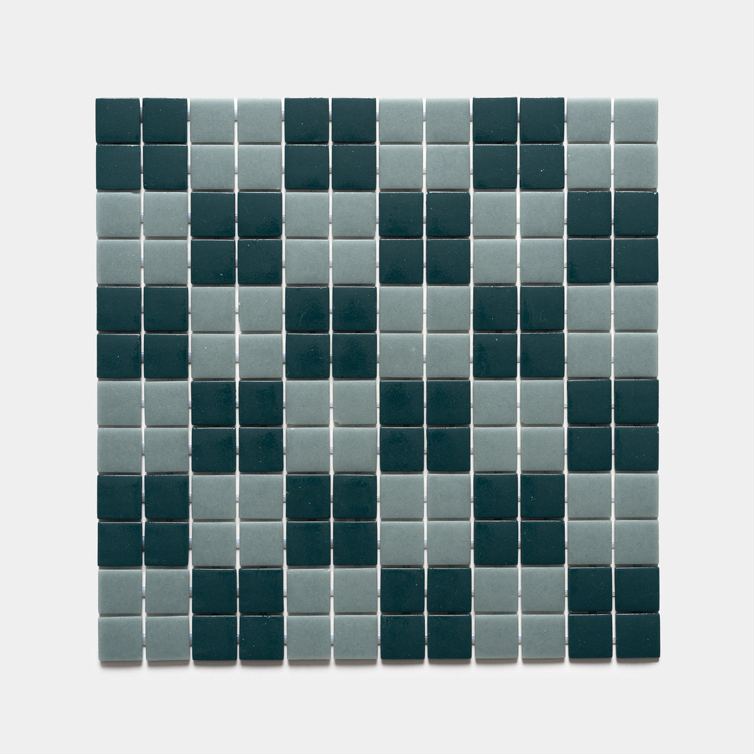 A grid of small square tiles from Zia Tile’s Cheque Vespertine + Marine Layer Sample forms a dark green X on a light gray background.