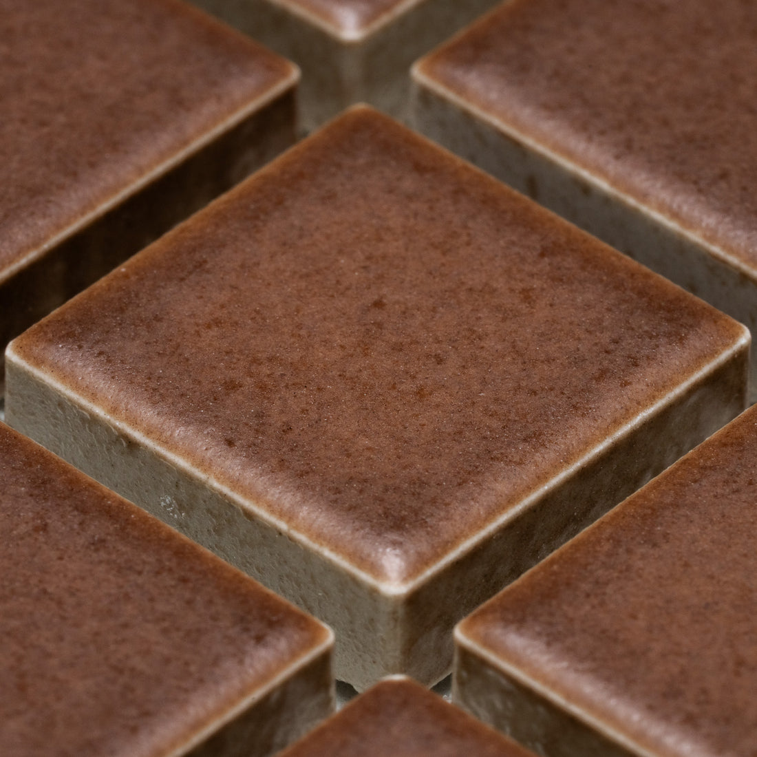 Close-up view of several neatly arranged, square-shaped Clove 1x1 tiles by Zia Tile, featuring smooth, matte surfaces and sharp edges.