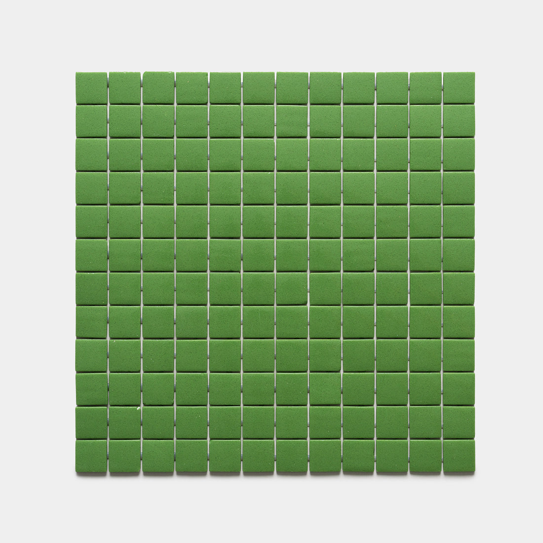 Clover 1x1 by Zia Tile features small, green rectangular tiles arranged in an even grid on a white background, creating a clean and uniform pattern.