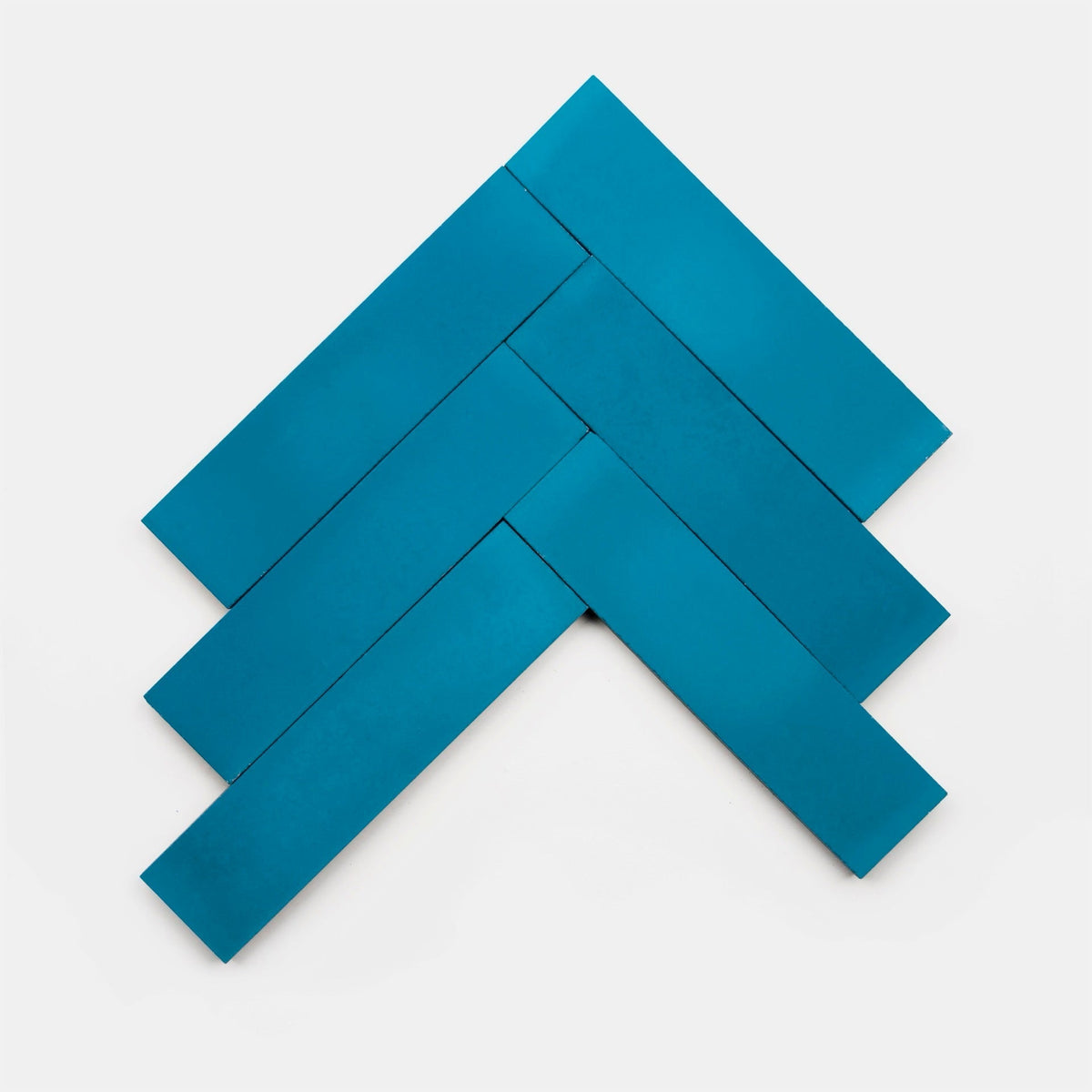 Five blue Cobalt 2x8 tiles from vendor-unknown, arranged in a herringbone pattern to form an upward-pointing arrow, showcase the artistry of handcrafted tile on a white background.