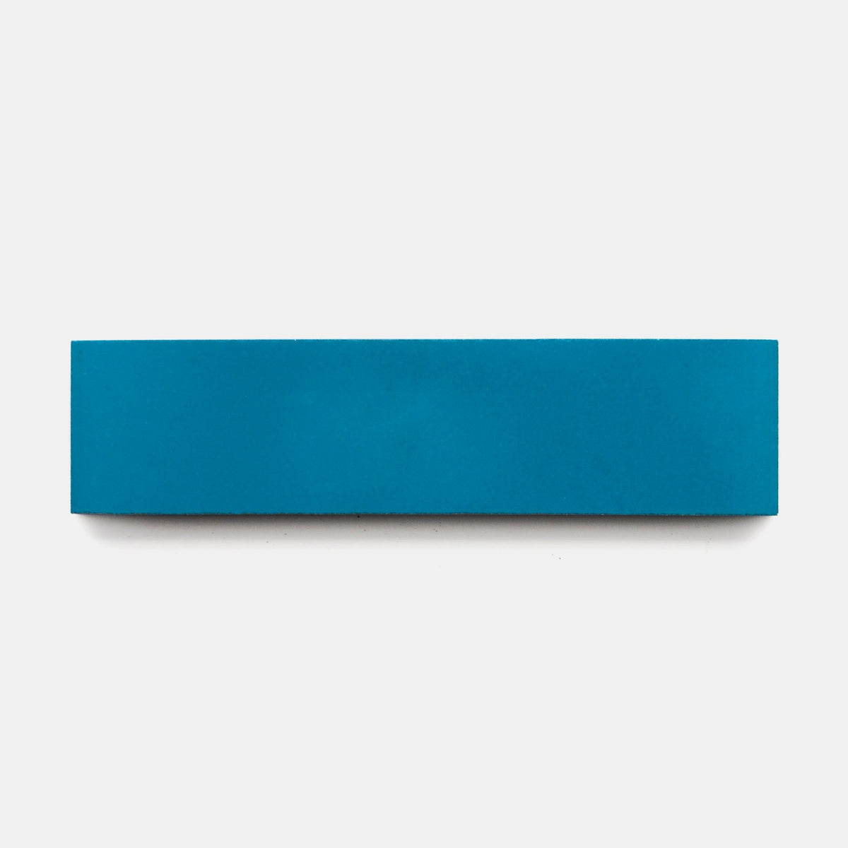 A sample of the vendor-unknown Cobalt 2x8 tile is displayed on a plain white background, highlighting its clean lines and bold blue color reminiscent of handcrafted cement tiles.