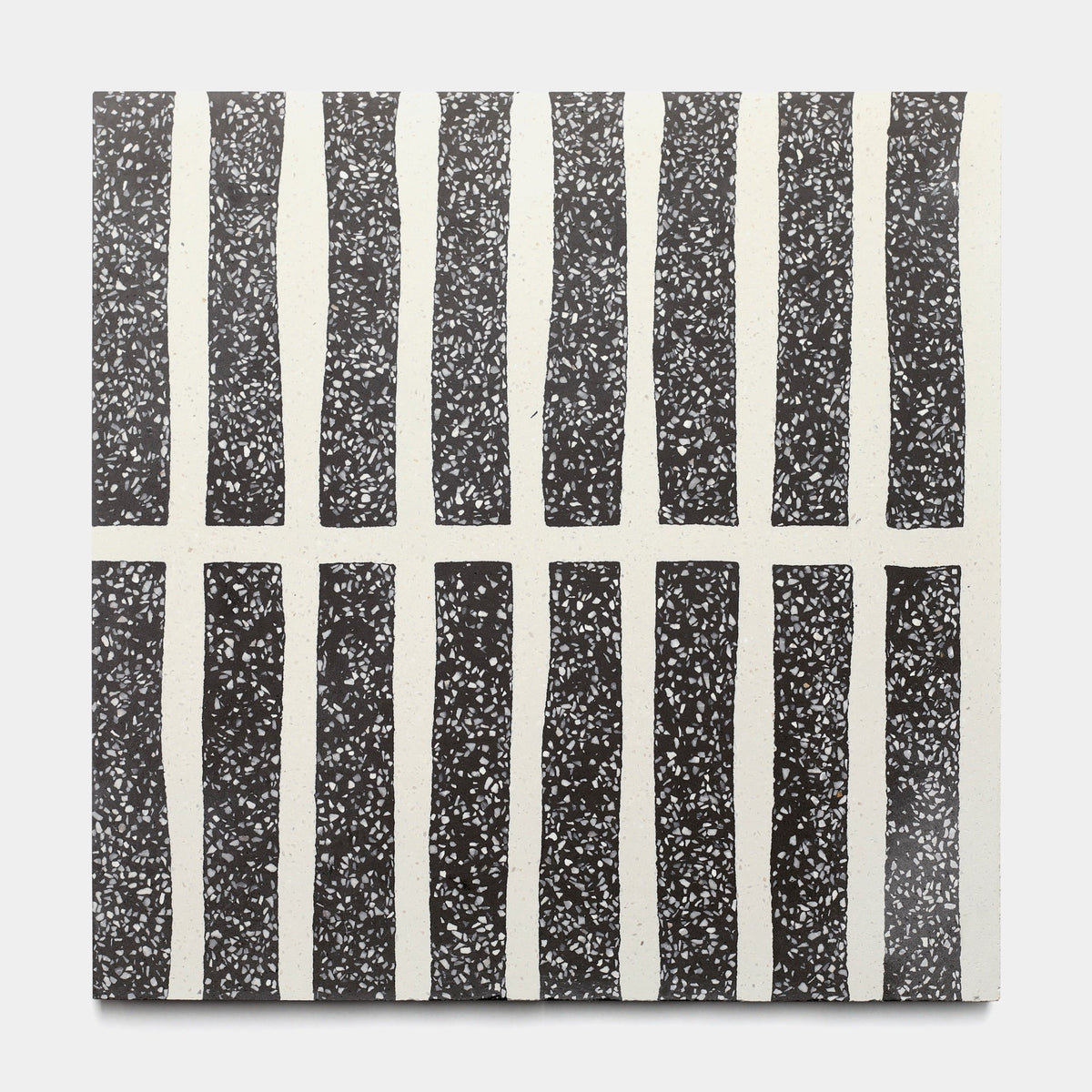The Collins Ash 12x12 sample by Zia Tile features a square, handmade-style design with alternating vertical black and white columns. Black columns have white speckles; white ones are plain, creating a unique grid effect.