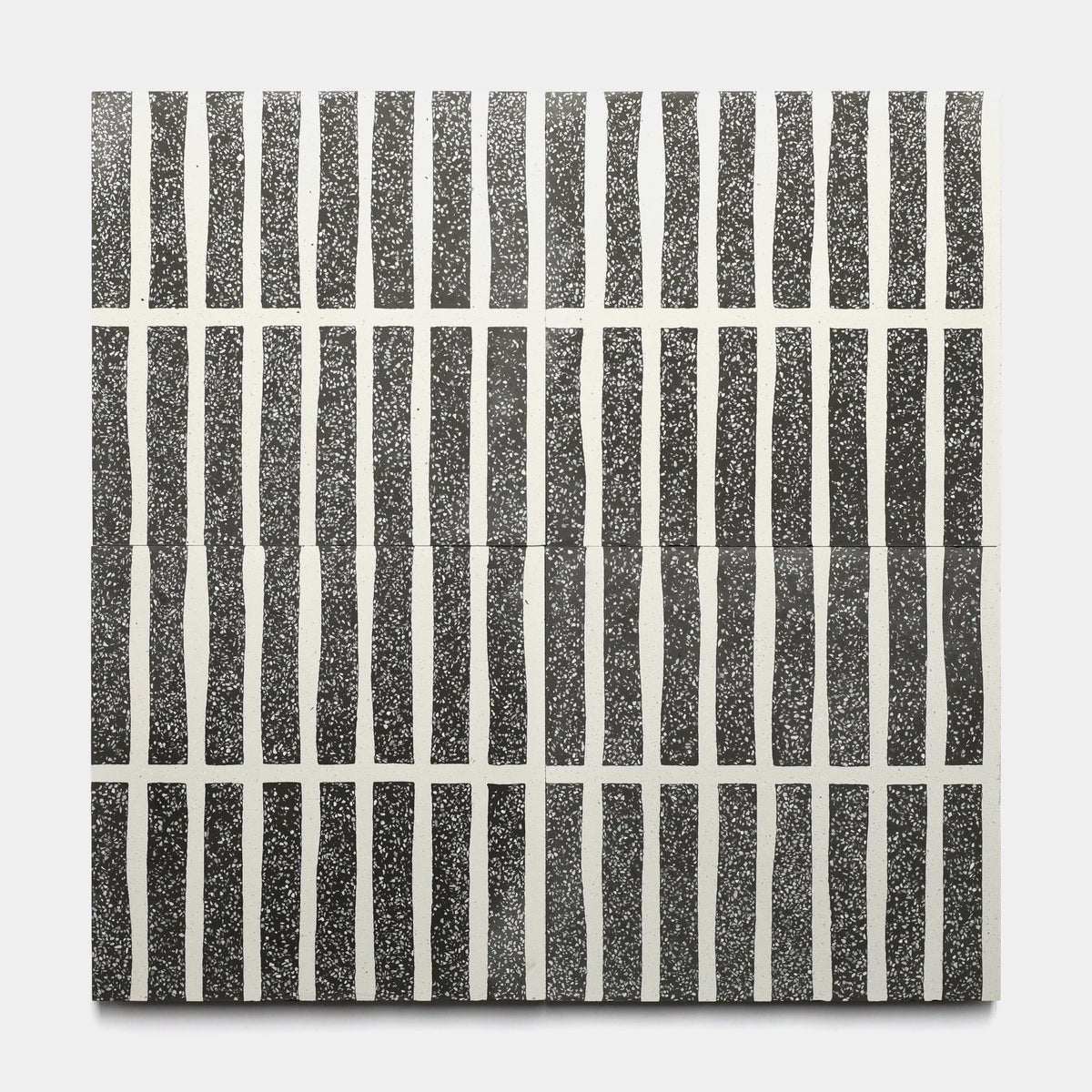 The Collins Ash 12x12 Sample by Zia Tile is a square tile featuring a grid of wavy black vertical lines with white spaces and a speckled texture, creating an abstract, hand-drawn look reminiscent of handmade tile designs.