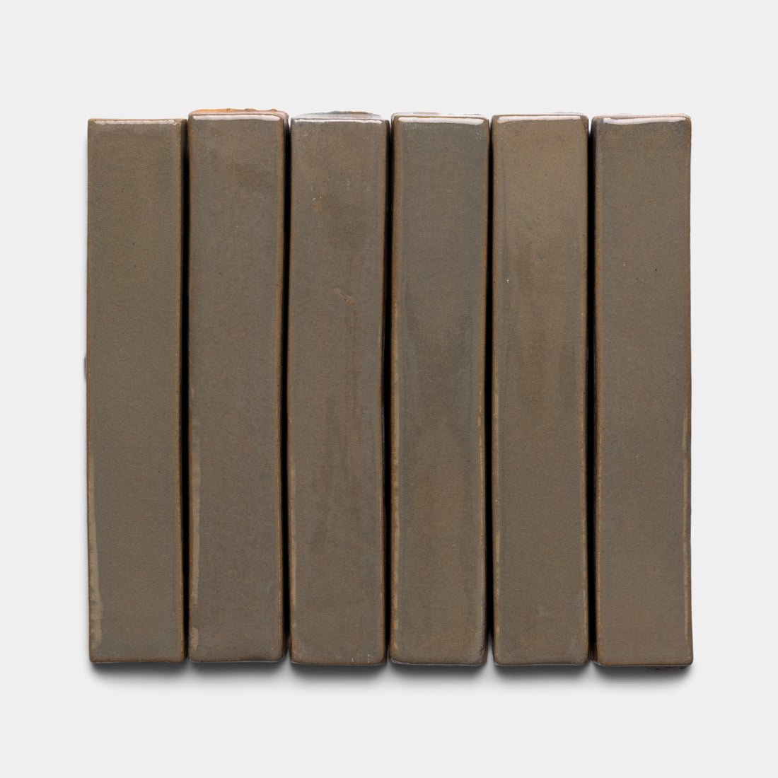 Six rectangular Condesa Mini Bar tiles from Zia Tile, in brown, are arranged vertically side by side against a plain white background.