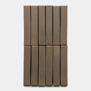 Twelve Condesa Mini Bars by Zia Tile, rectangular and brown, are arranged vertically in two columns of six on a plain white background.