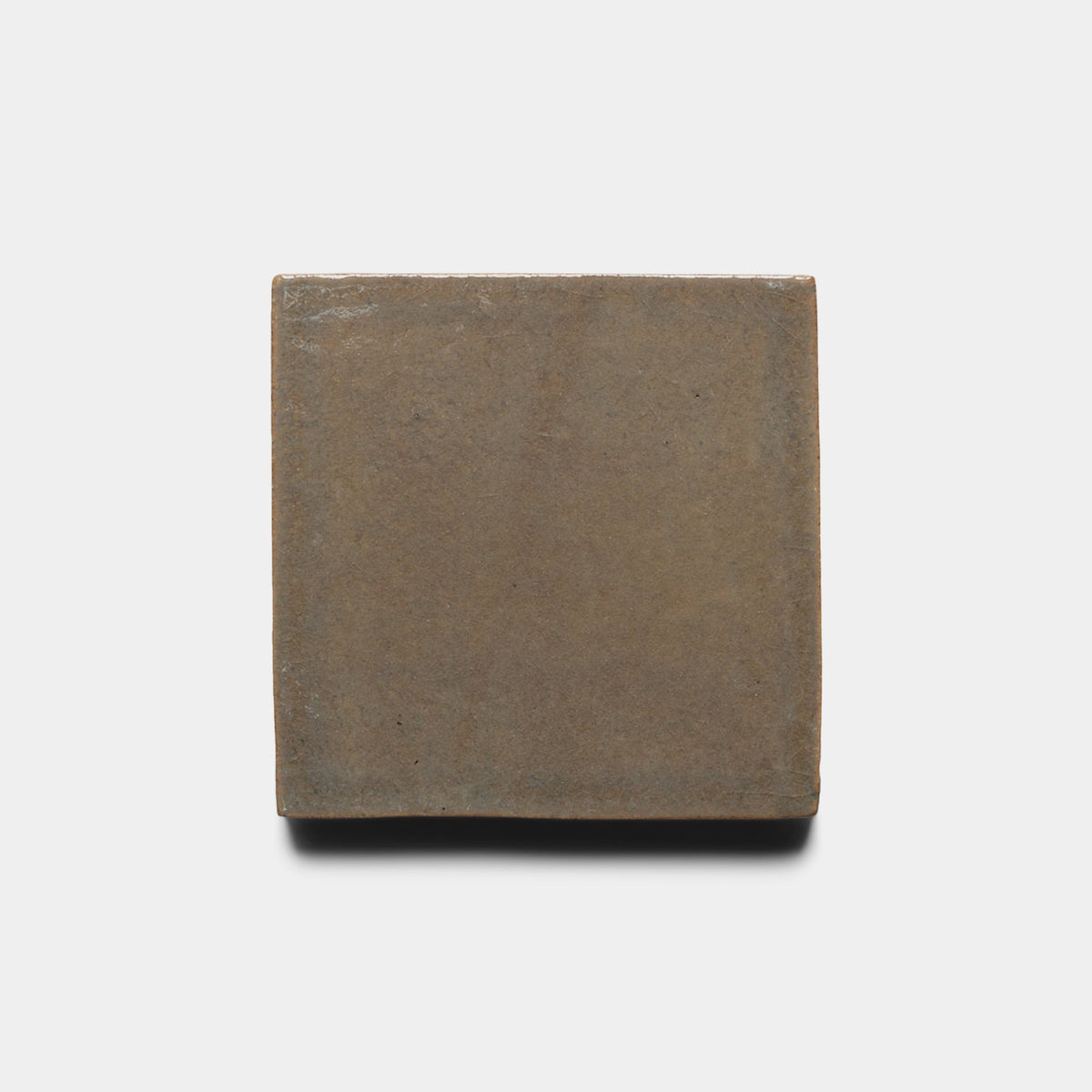 A single Condesa 4x4 Square sample by Zia Tile, featuring a matte brown ceramic finish, is centered against a plain white background with a soft shadow beneath it.