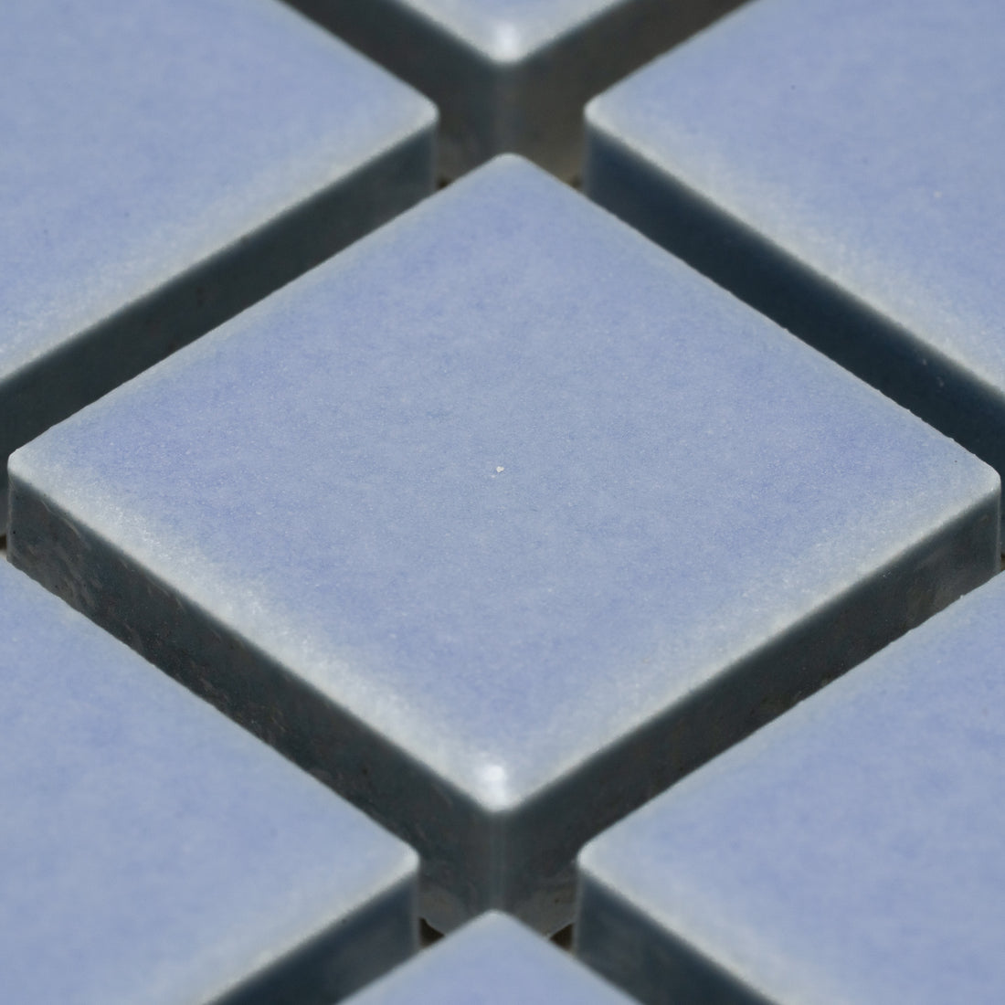 Close-up of Zia Tile’s Cornflower 1x1 tiles, light blue and square, arranged in a grid with visible gaps that form a diamond-shaped pattern.