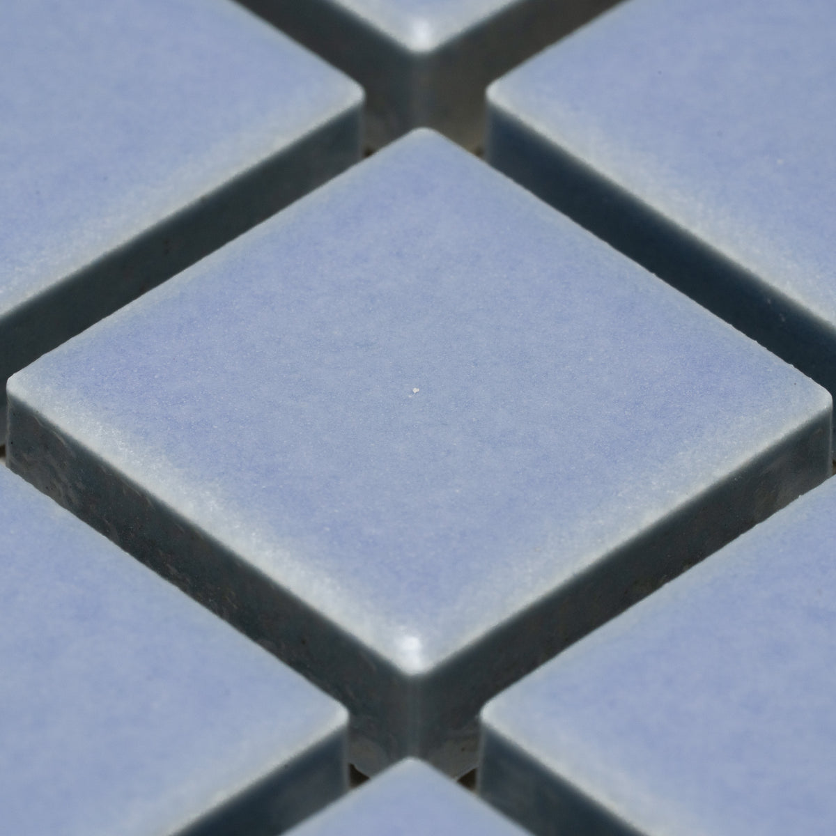 Close-up of Zia Tile’s Cornflower 1x1 tiles, light blue and square, arranged in a grid with visible gaps that form a diamond-shaped pattern.