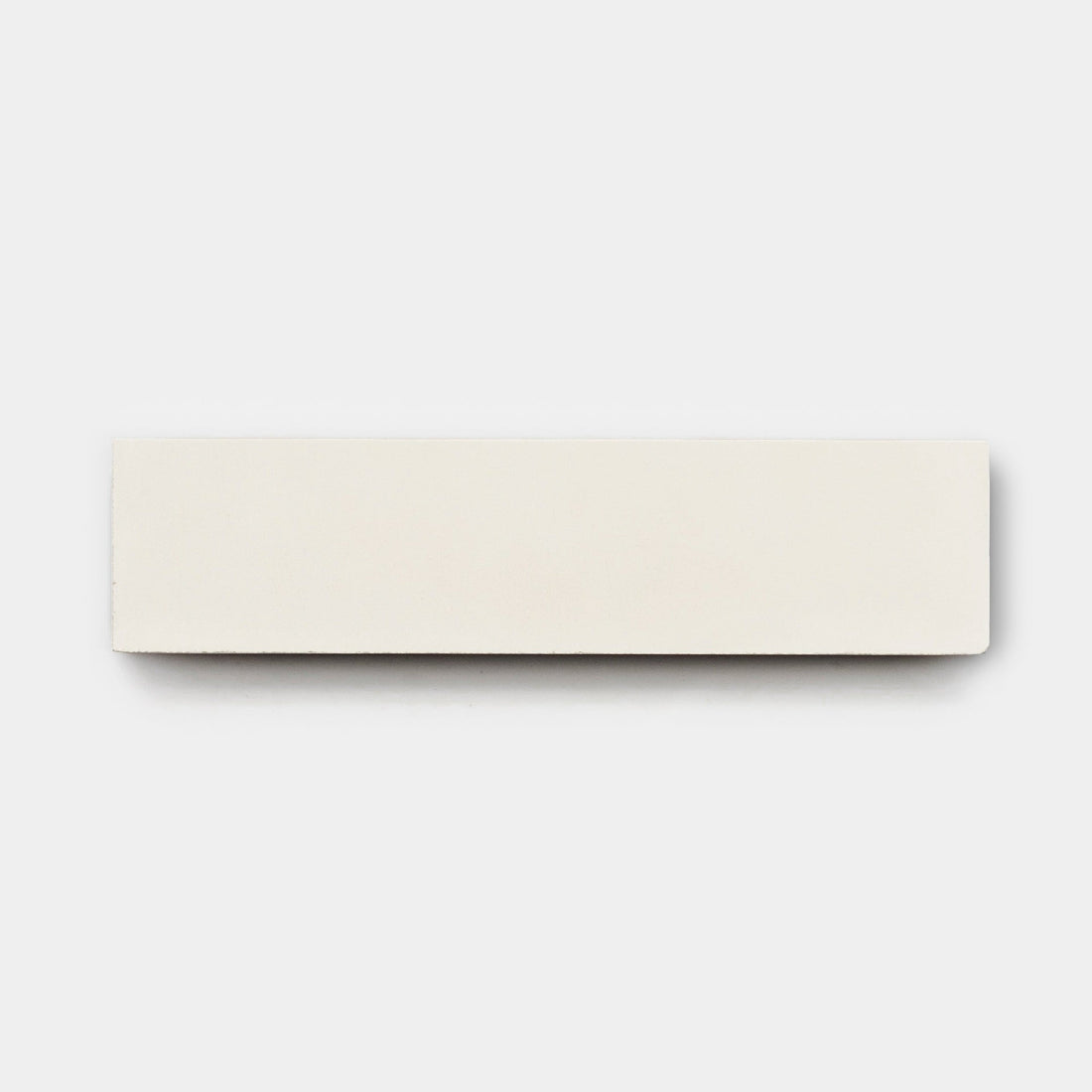 A rectangular white Cotton 2x8, Sample by vendor-unknown is placed on a plain light gray background, its crisp edges reminiscent of handmade or cement tile designs.