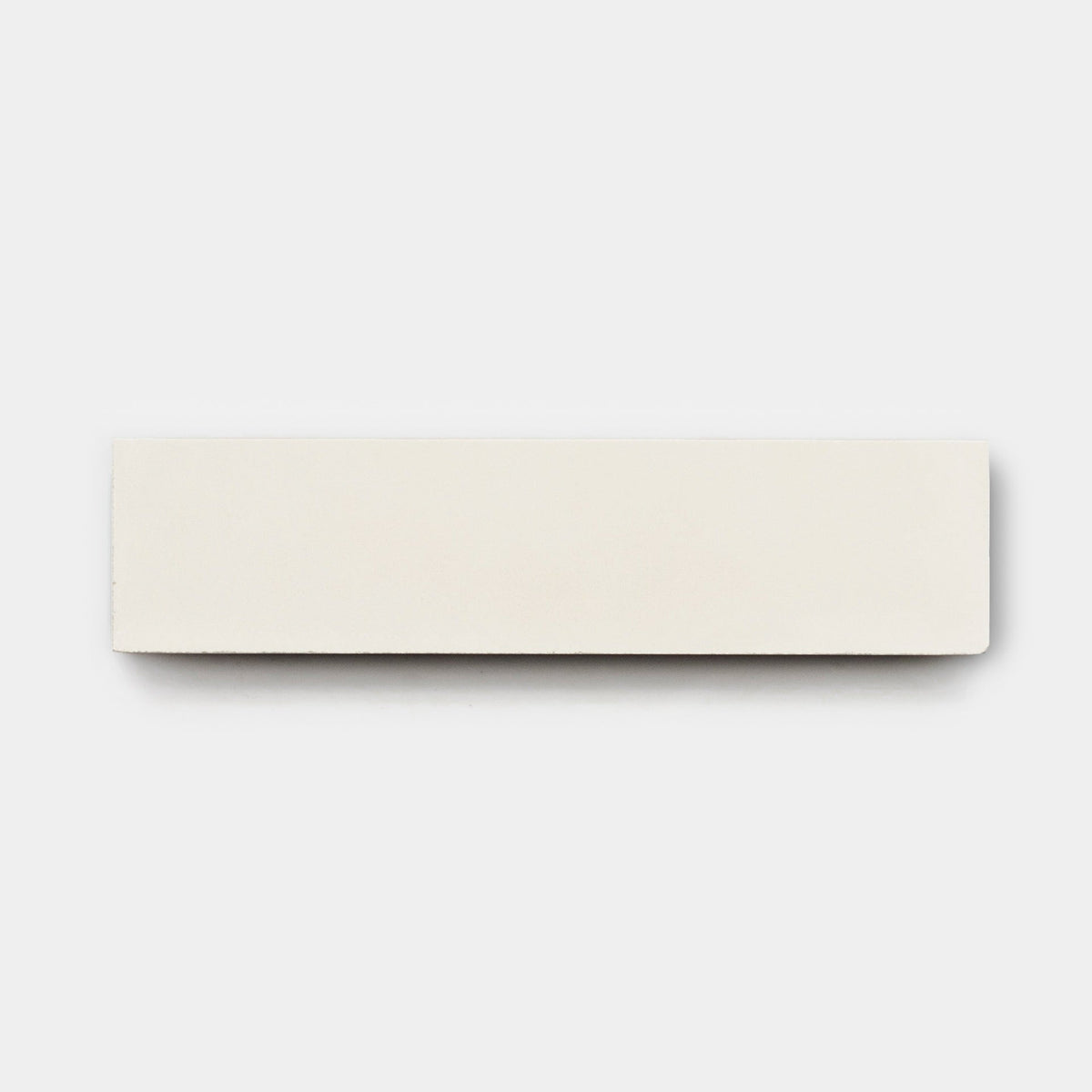 A rectangular white Cotton 2x8, Sample by vendor-unknown is placed on a plain light gray background, its crisp edges reminiscent of handmade or cement tile designs.