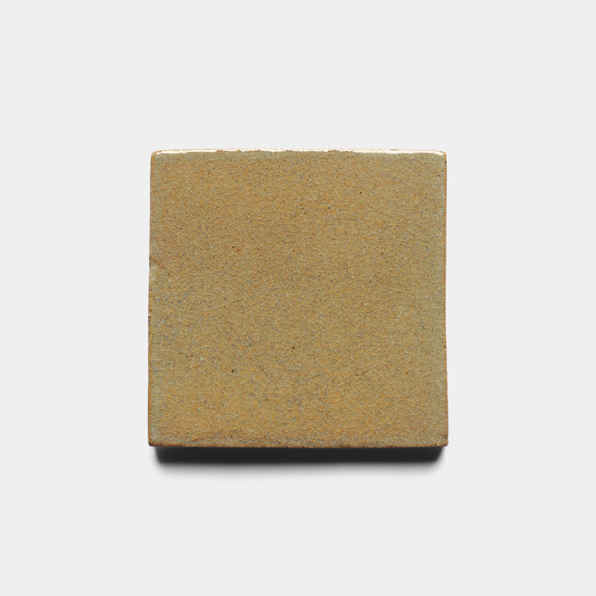 The Zia Tile Creosote 4x4 Square Sample is a handmade, flat, tan tile displayed on a plain white background with a subtle shadow.