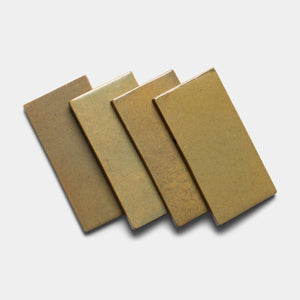 Four Creosote 4x8 Rectangle ceramic tiles by Zia Tile, in light brown and tan matte finishes, are arranged in a slightly overlapping diagonal row on a white background.