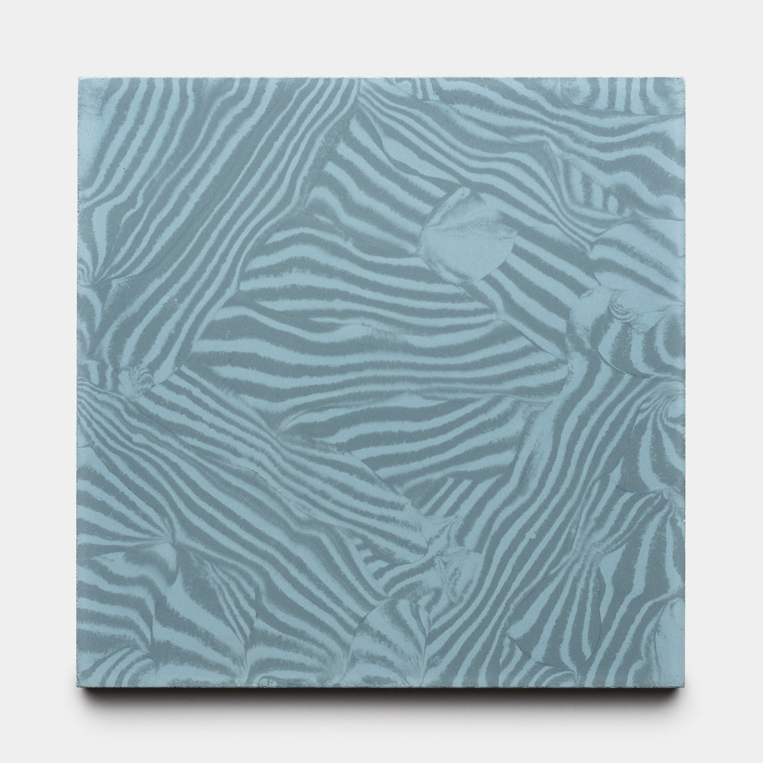 The Currents Slate + Hyannis 8x8 by Zia Tile is a square tile featuring an abstract pattern of overlapping zebra stripes in light blue and gray tones.