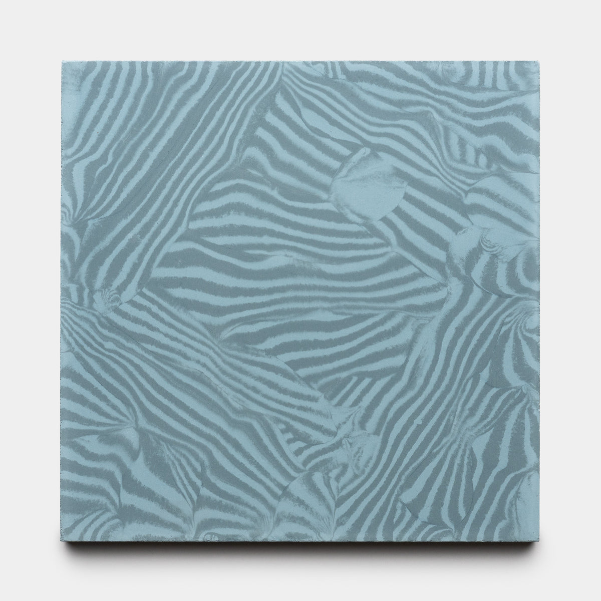The Currents Slate + Hyannis 8x8 by Zia Tile is a square tile featuring an abstract pattern of overlapping zebra stripes in light blue and gray tones.