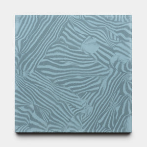 The Currents Slate + Hyannis 8x8 by Zia Tile is a square tile featuring an abstract pattern of overlapping zebra stripes in light blue and gray tones.