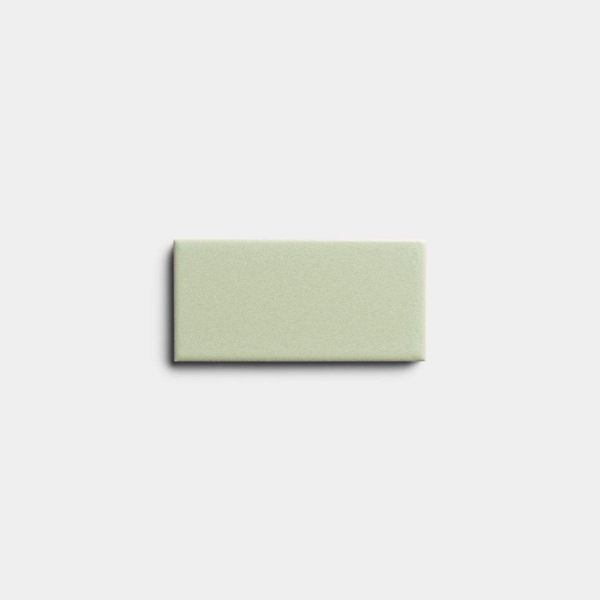 A single, rectangular Cypress 2x4 tile sample by Zia Tile in light green with a smooth matte finish is centered on a plain, light gray background.