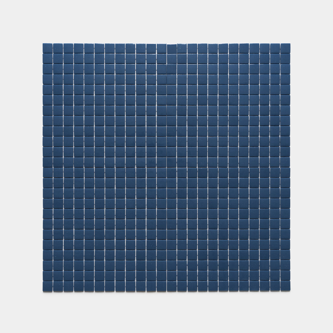 The Zia Tile Damascus 1x1 features evenly spaced, dark blue square tiles set on a light gray background, creating a neat rectangular grid pattern.